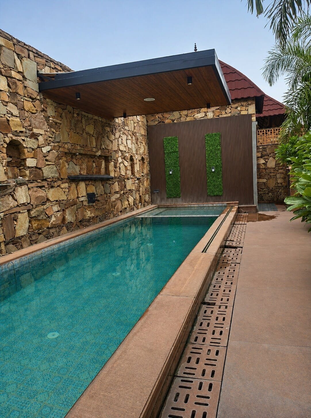 Narrow pool beside stone walls under a covered wooden roof