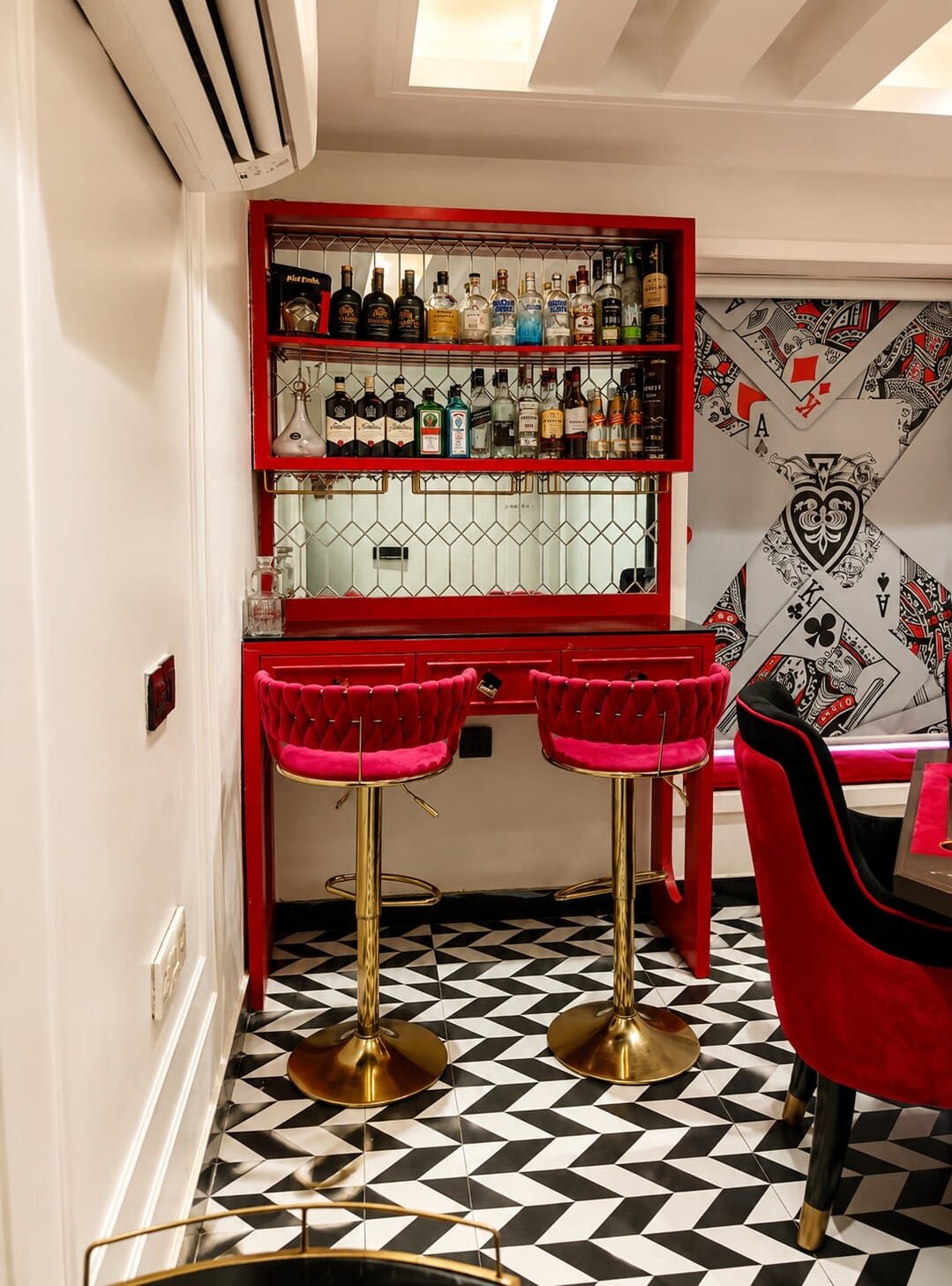 Bar corner with red shelving, glassware and brass bar stools