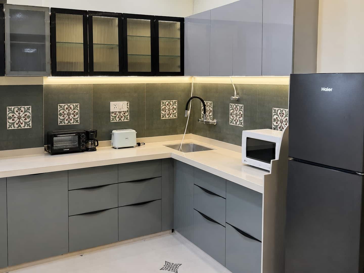 Kitchen with grey cabinets, patterned tile backsplash, microwave and fridge