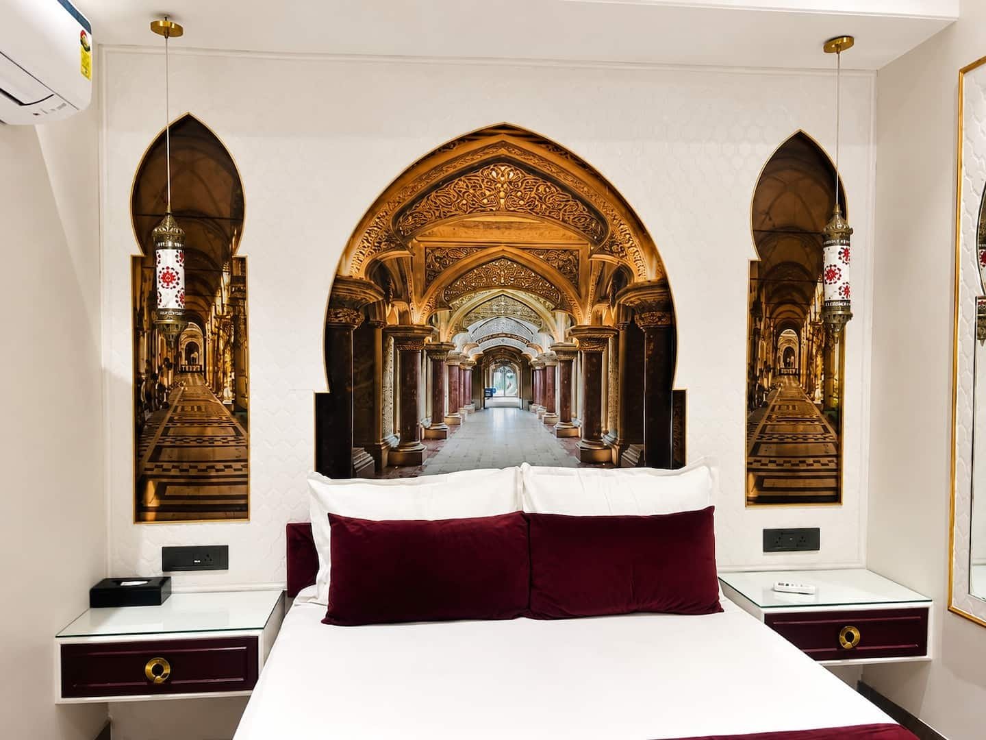 Bedroom 1 bed framed by a mural of an arched gallery