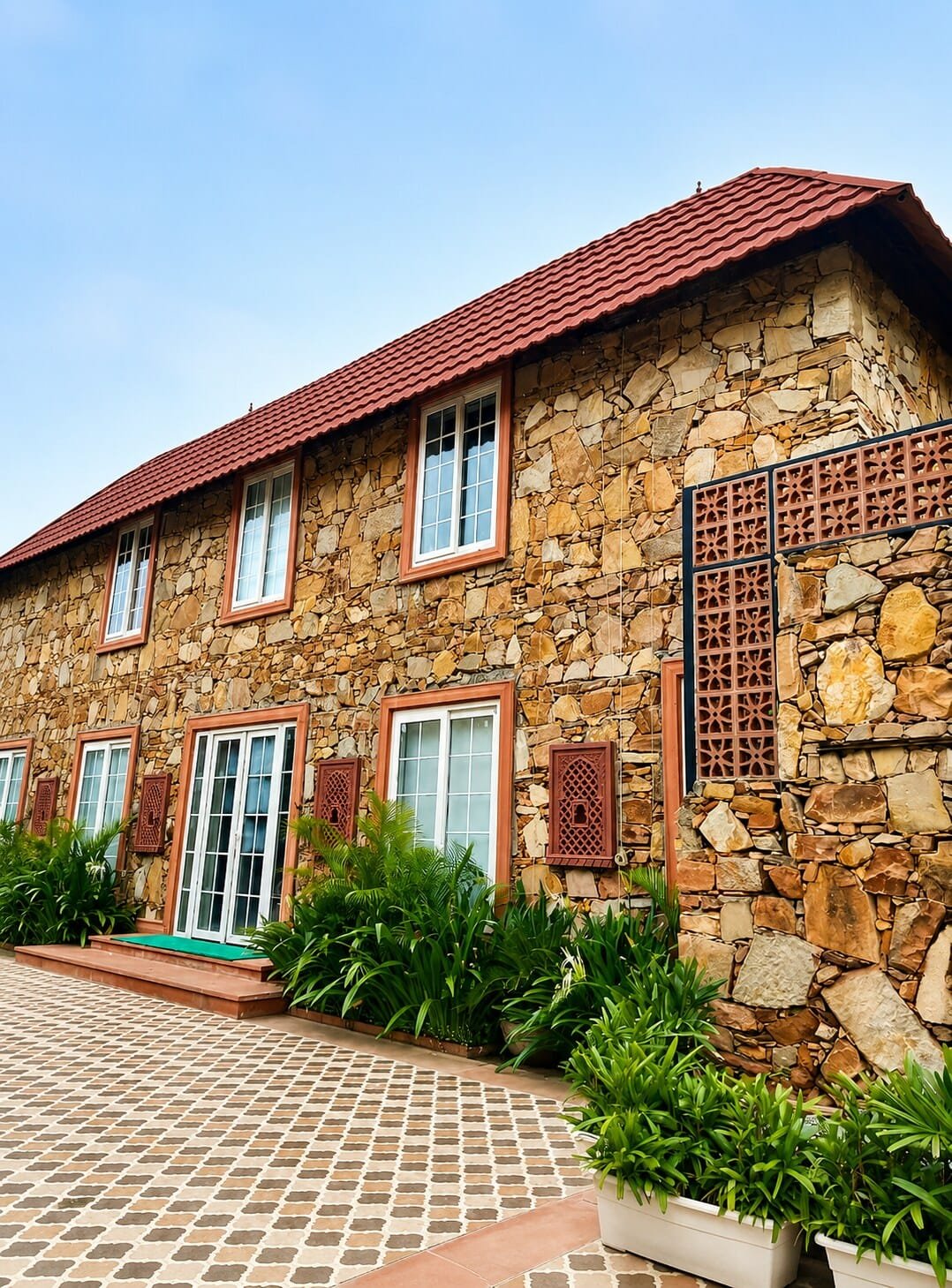 Stone villa with a red tiled roof, patterned paving and planters