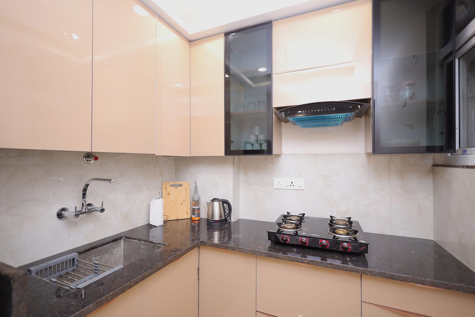 Kitchen counter with a gas hob, kettle and beige overhead cabinets