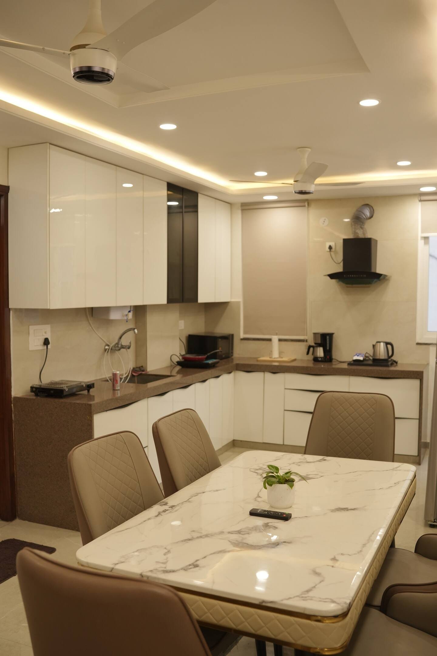 Kitchen with glossy white cabinets and a marble-top dining table in front