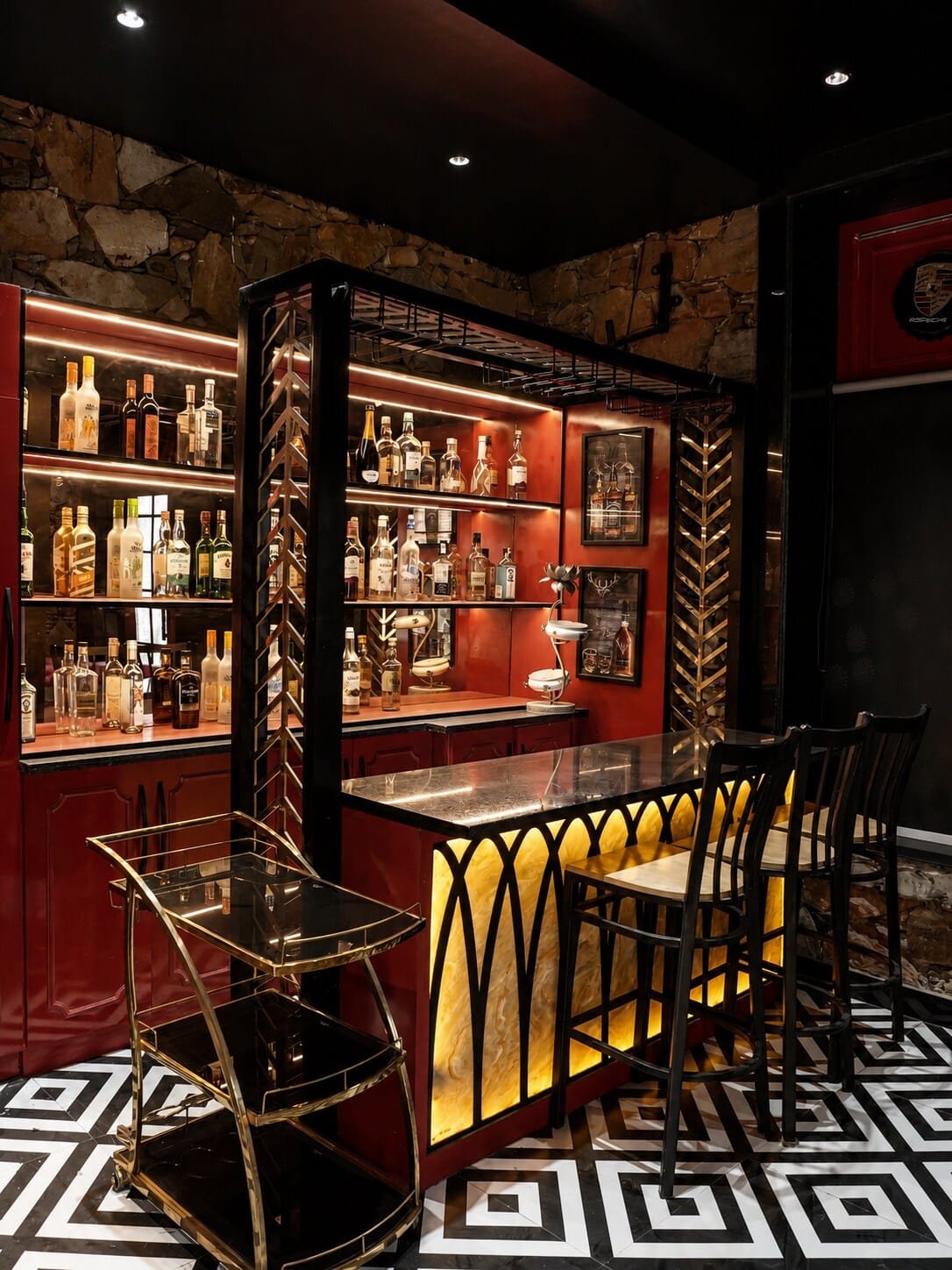 Bar with red shelving and stone walls, lit from beneath the counter