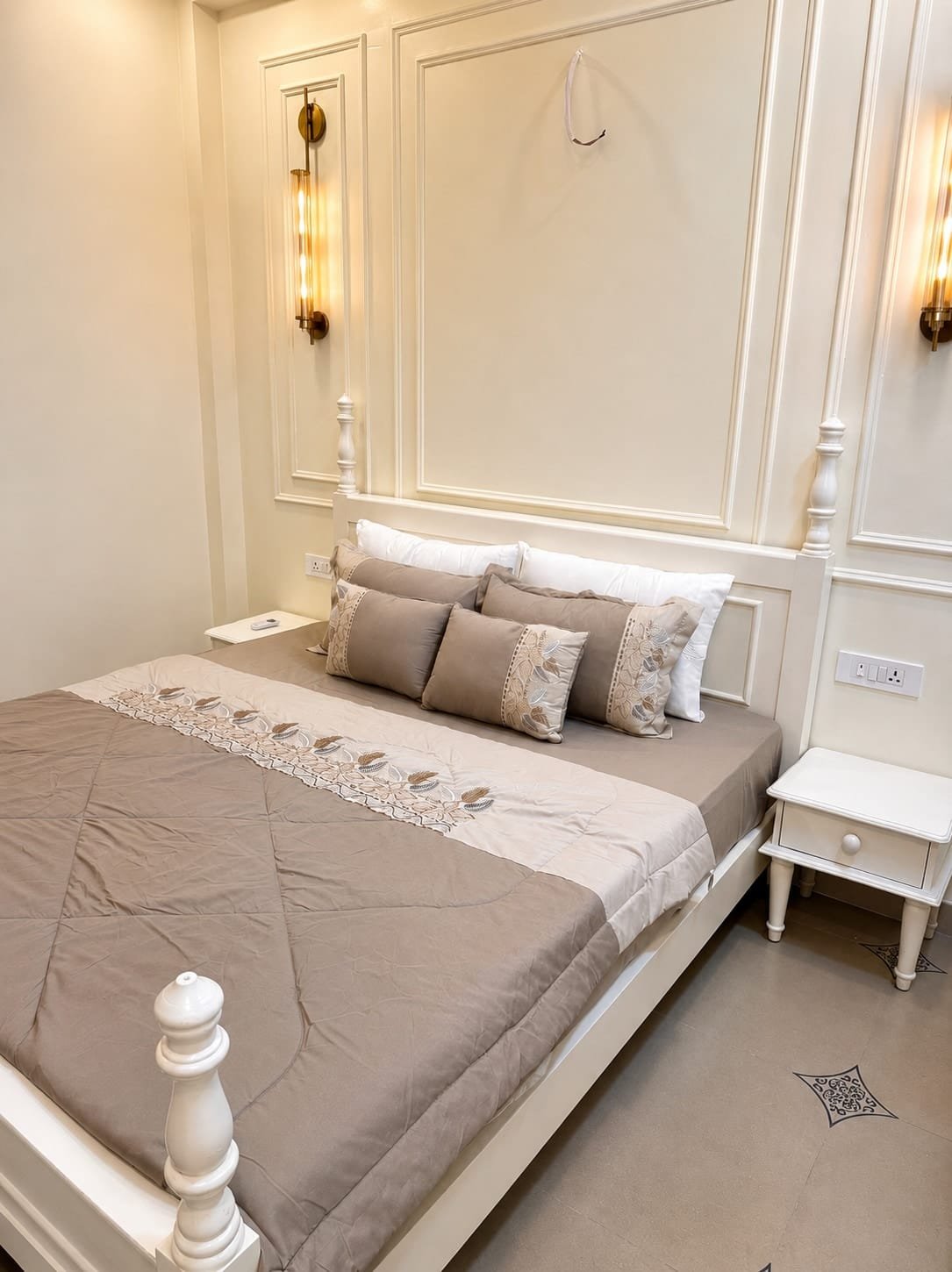 King bed with a white carved footboard against panelled walls