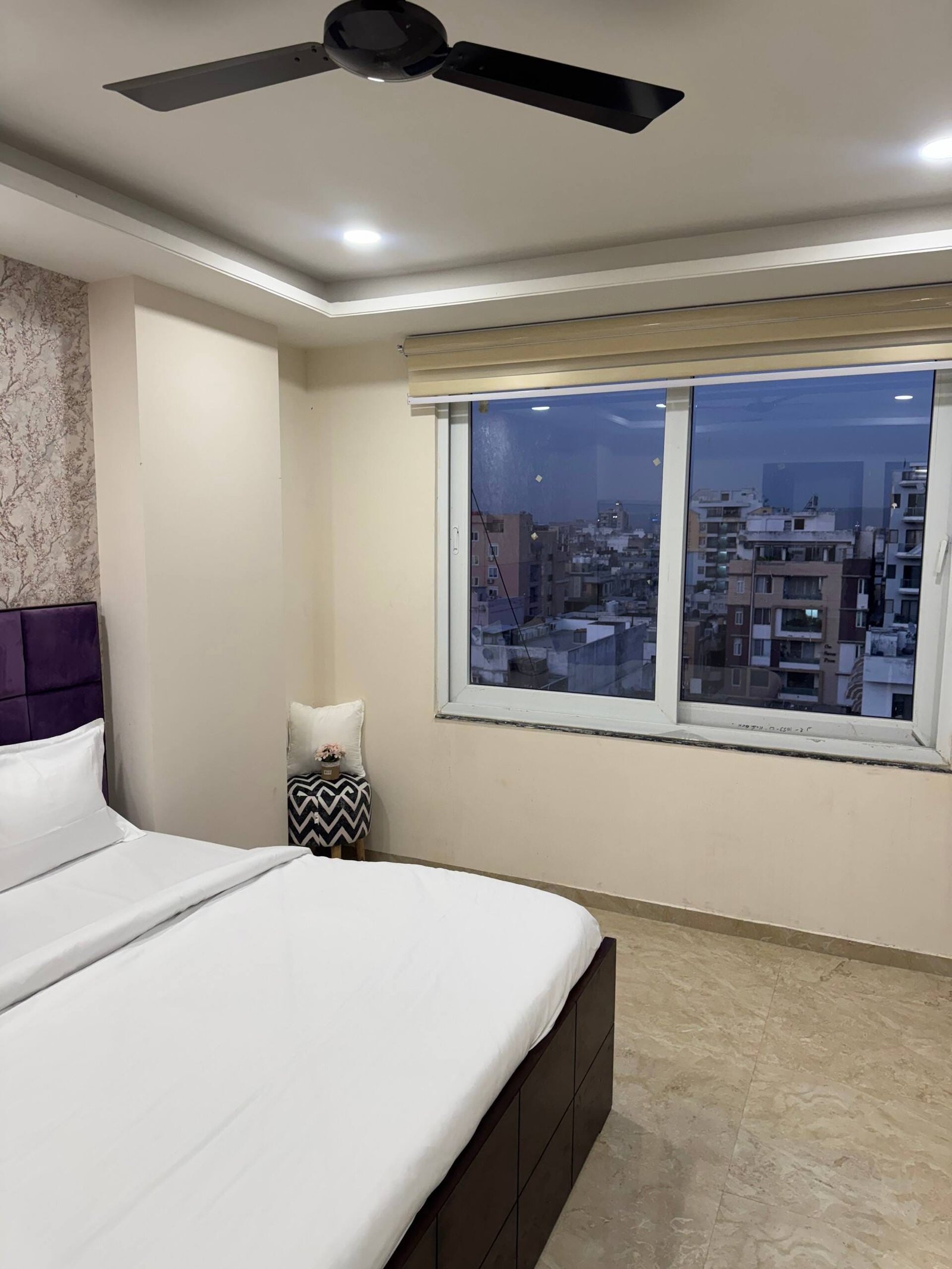 Bedroom 1 with a large window showing the city at dusk