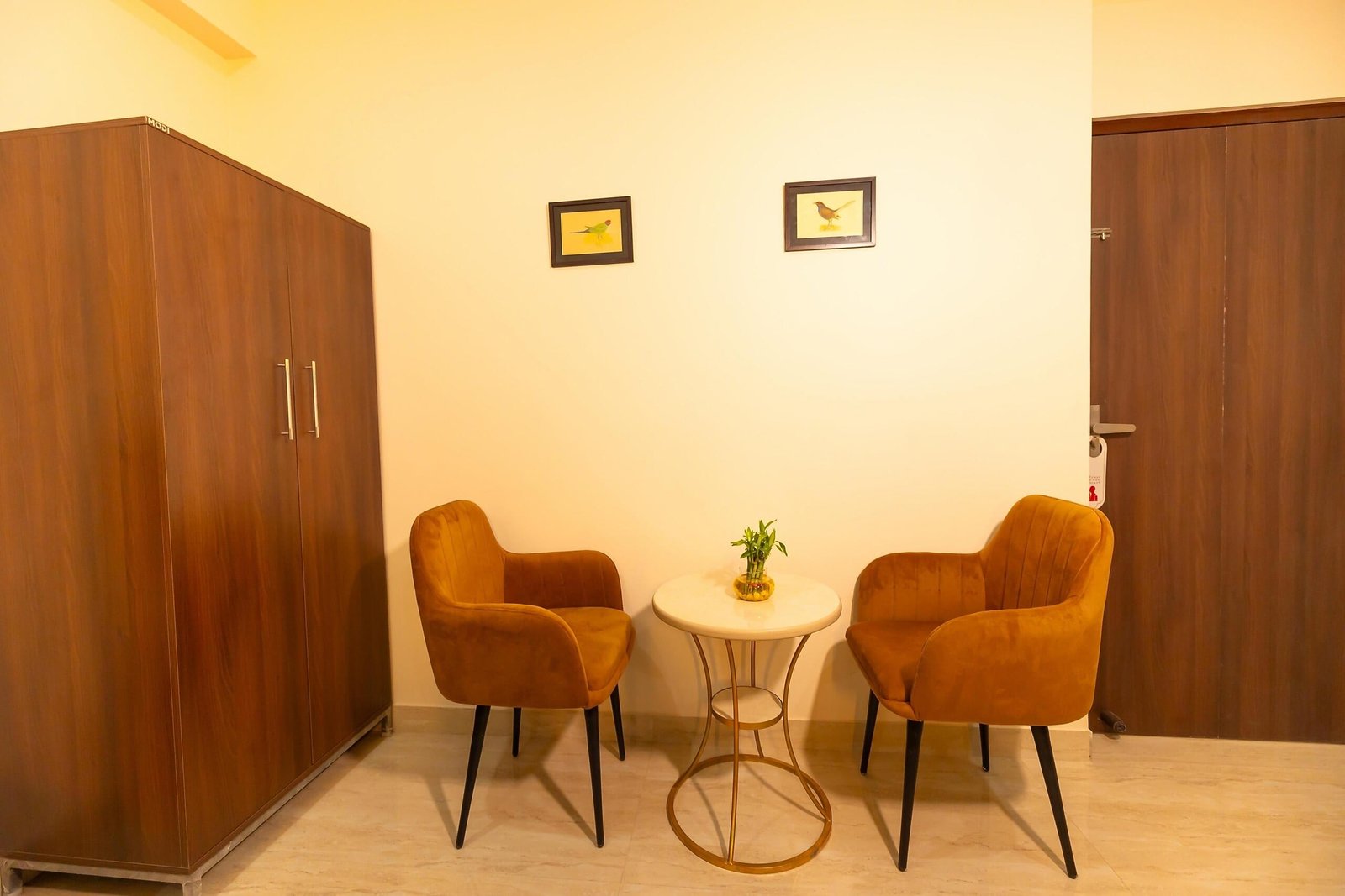 Two tan velvet armchairs around a small round table beside the wardrobe