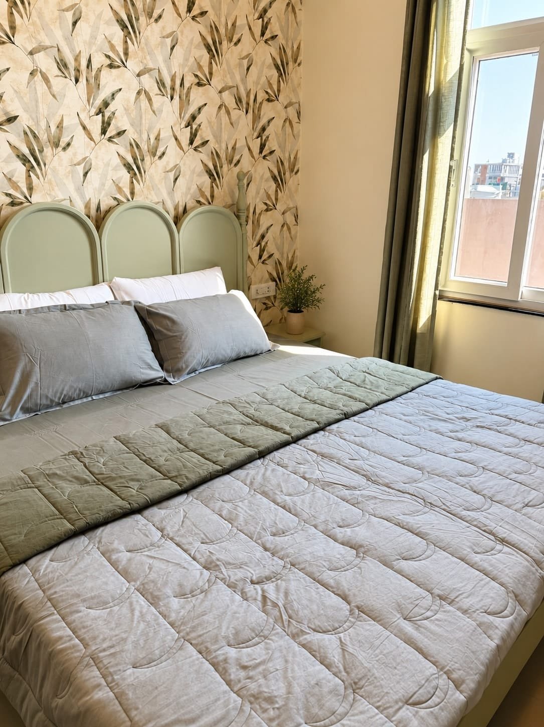 Bedroom 2 with a green scalloped headboard against leaf-print wallpaper