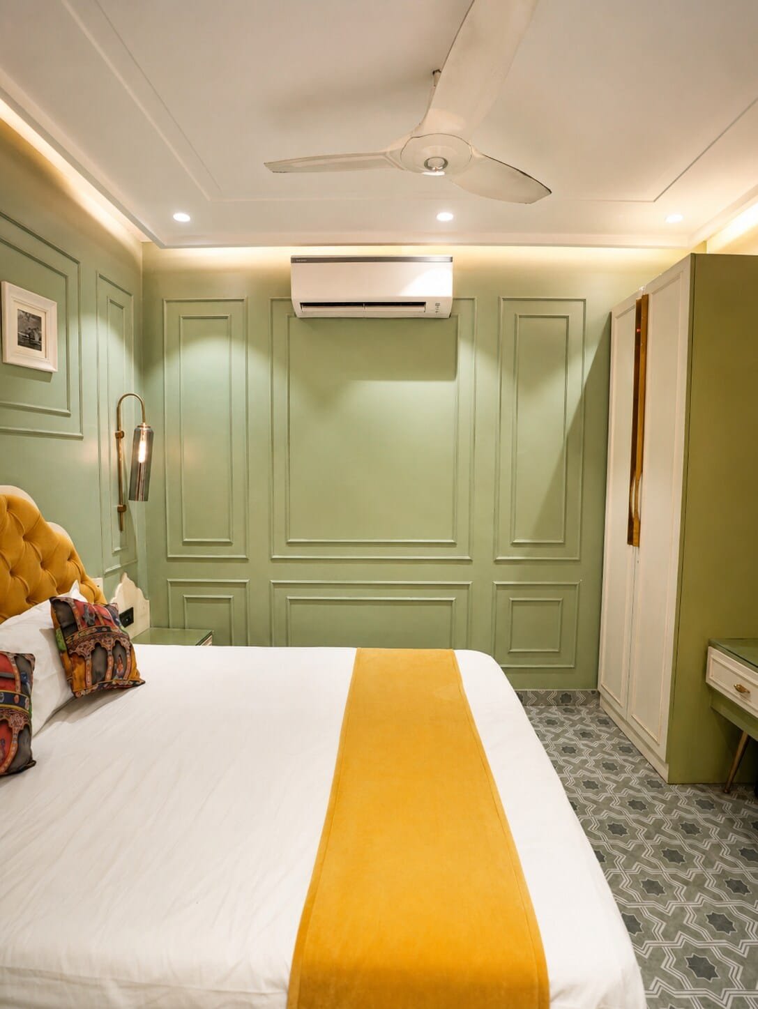 Bedroom 2 with sage green panelled walls and a mustard bed runner
