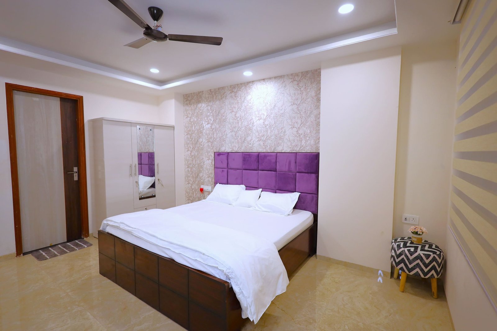 Bedroom 3 with a purple tufted headboard, ceiling fan and side stool