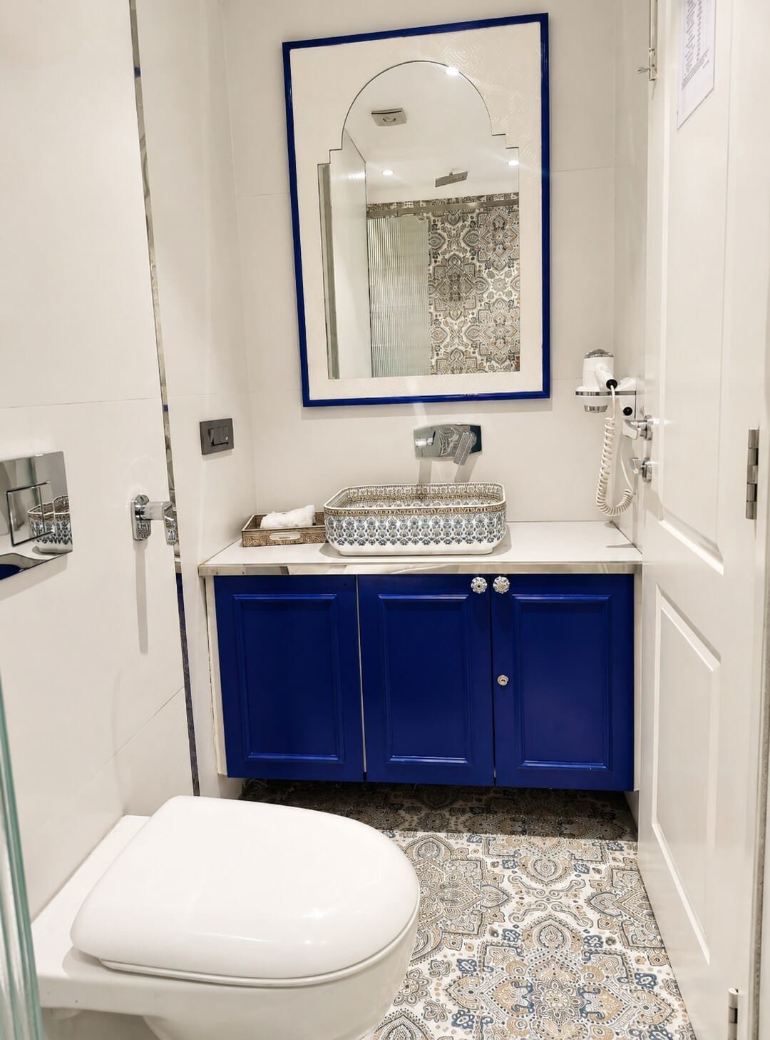 Bathroom with a blue vanity and patterned floor tiles