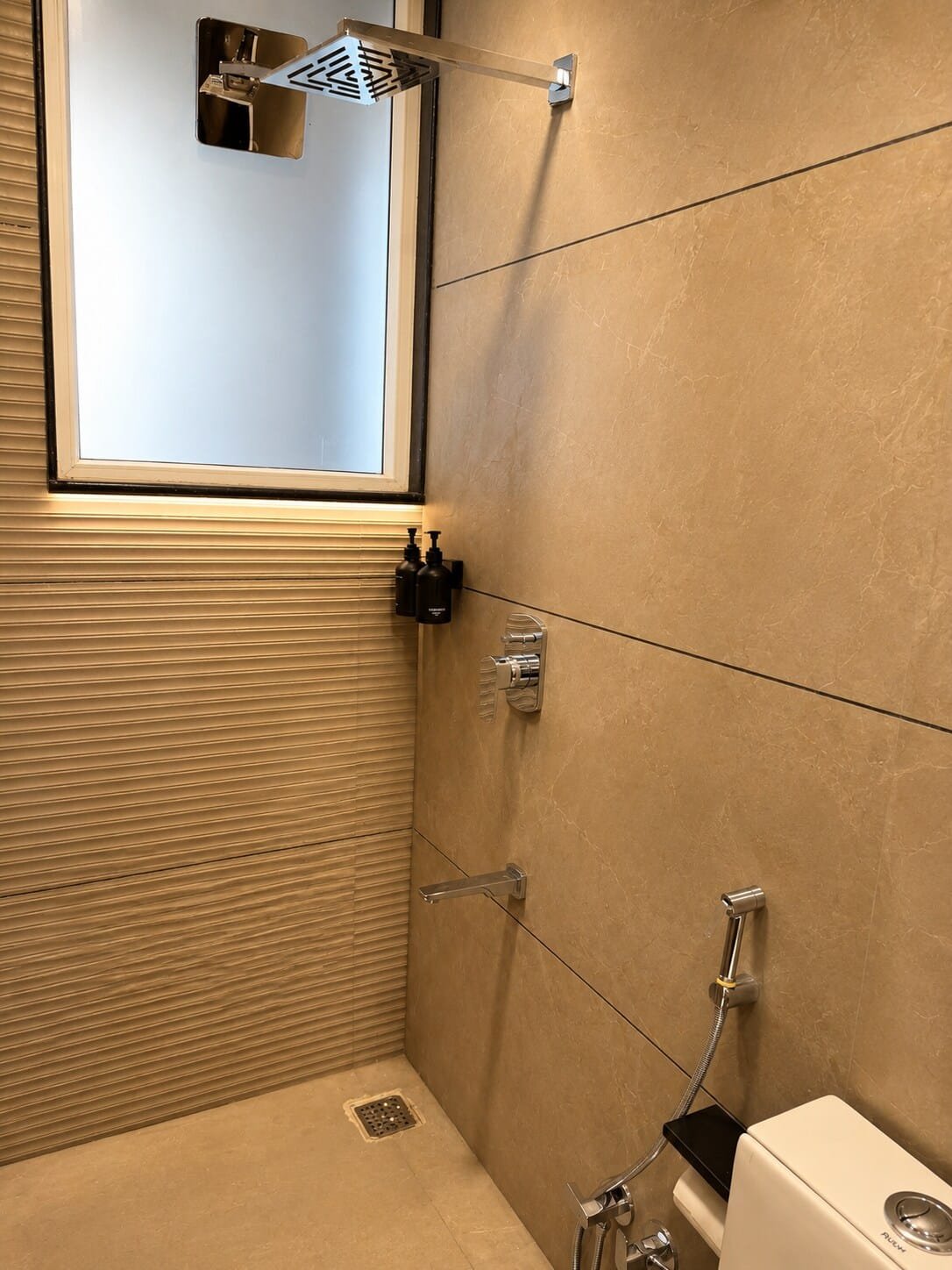 Walk-in shower with a rain shower head and beige tiles
