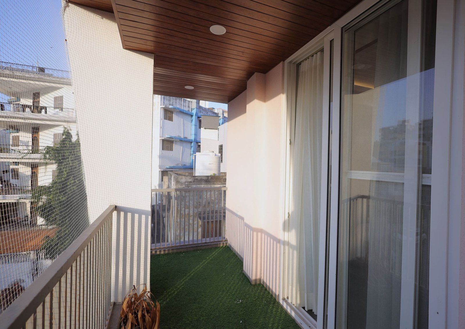 Balcony with a railing and artificial lawn, overlooking nearby buildings