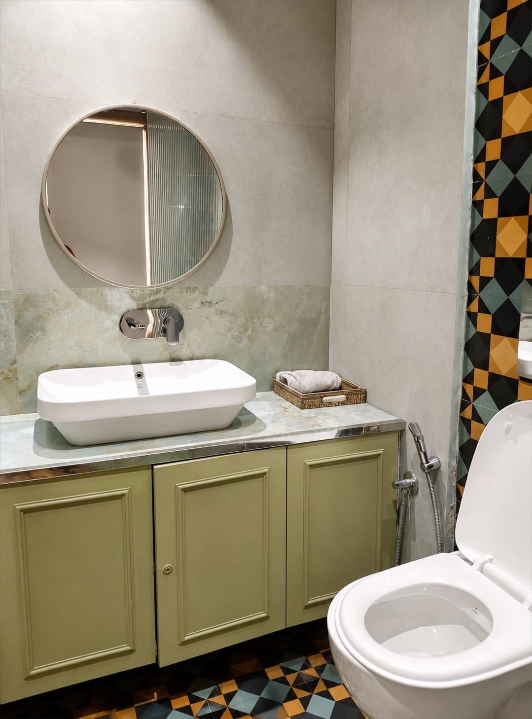 Bathroom with a round mirror, vessel basin and sage vanity