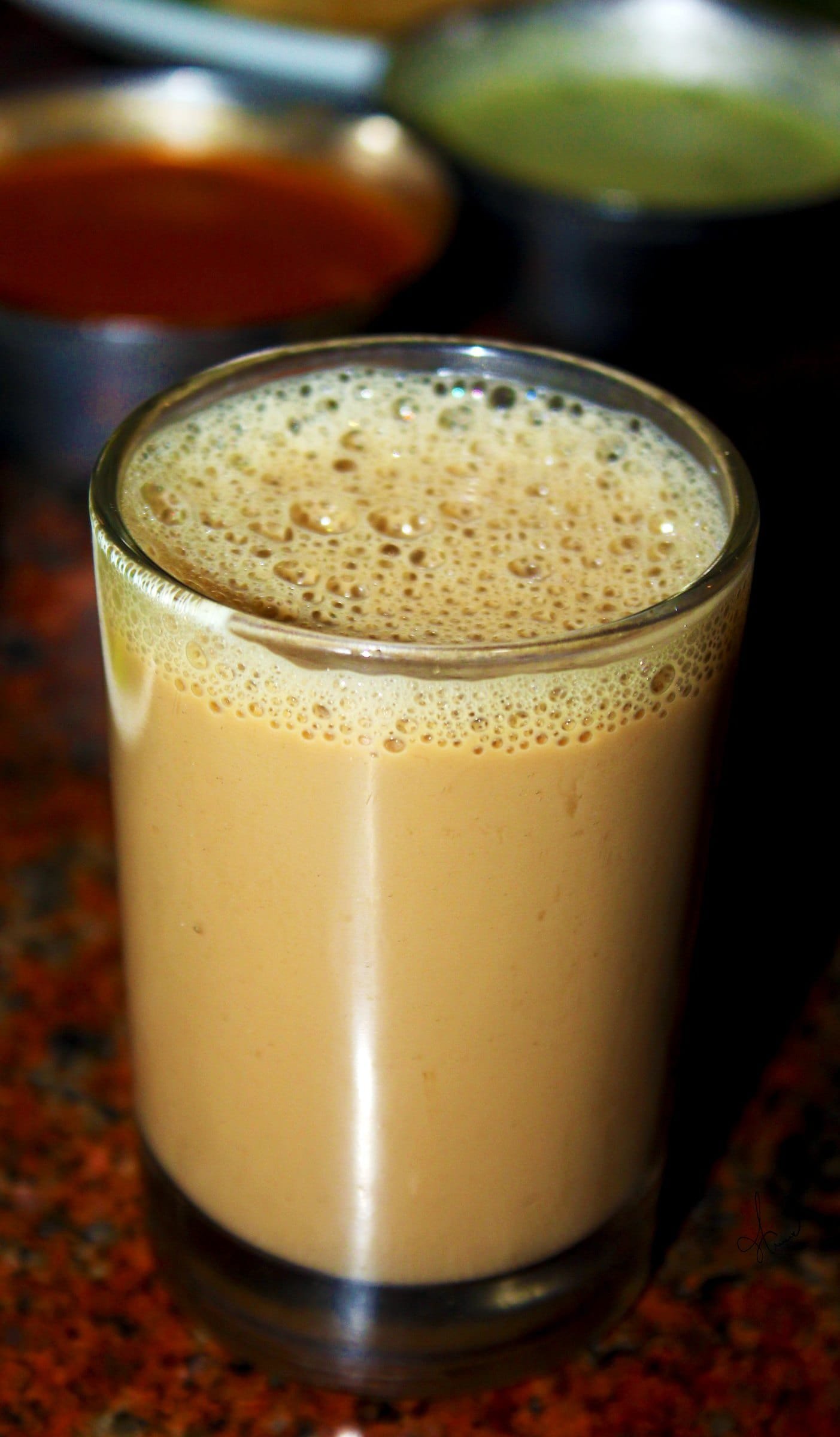 A glass of milky chai with froth on top