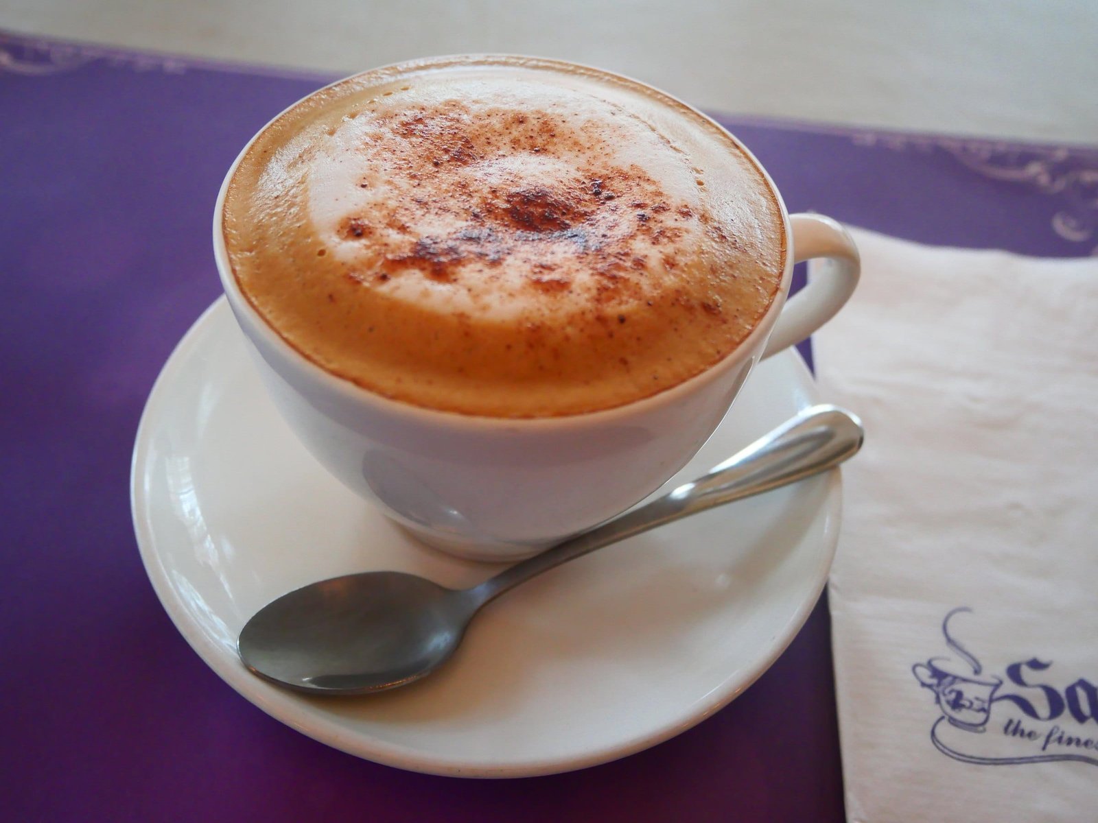 A cappuccino with cocoa on the foam, on a white saucer