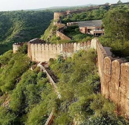 The fort walls of Nahargarh running along a green hillside